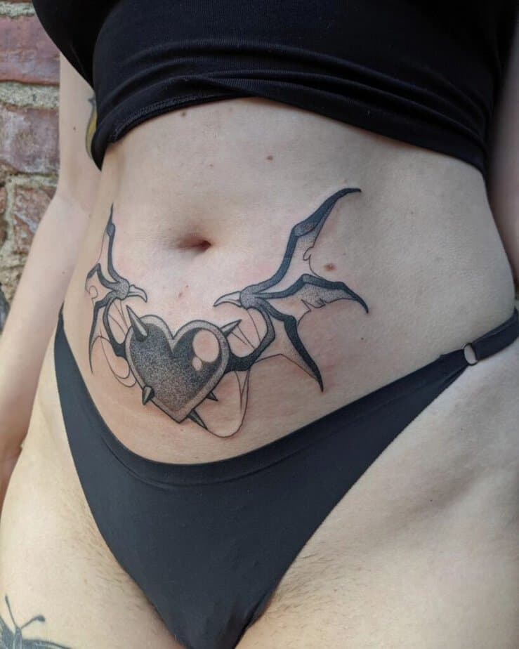 17. Ein Bauchdecken-Tattoo mit einem Herz mit Hörnern und Dämonenflügeln