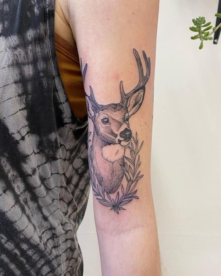 15. Ein Hirsch-Tattoo mit Blättern auf dem Oberarm