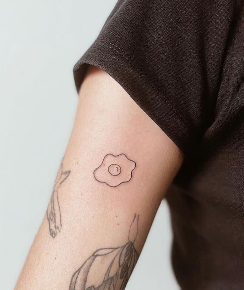 7. Ein kleines und einfaches Ei-Tattoo auf dem Oberarm