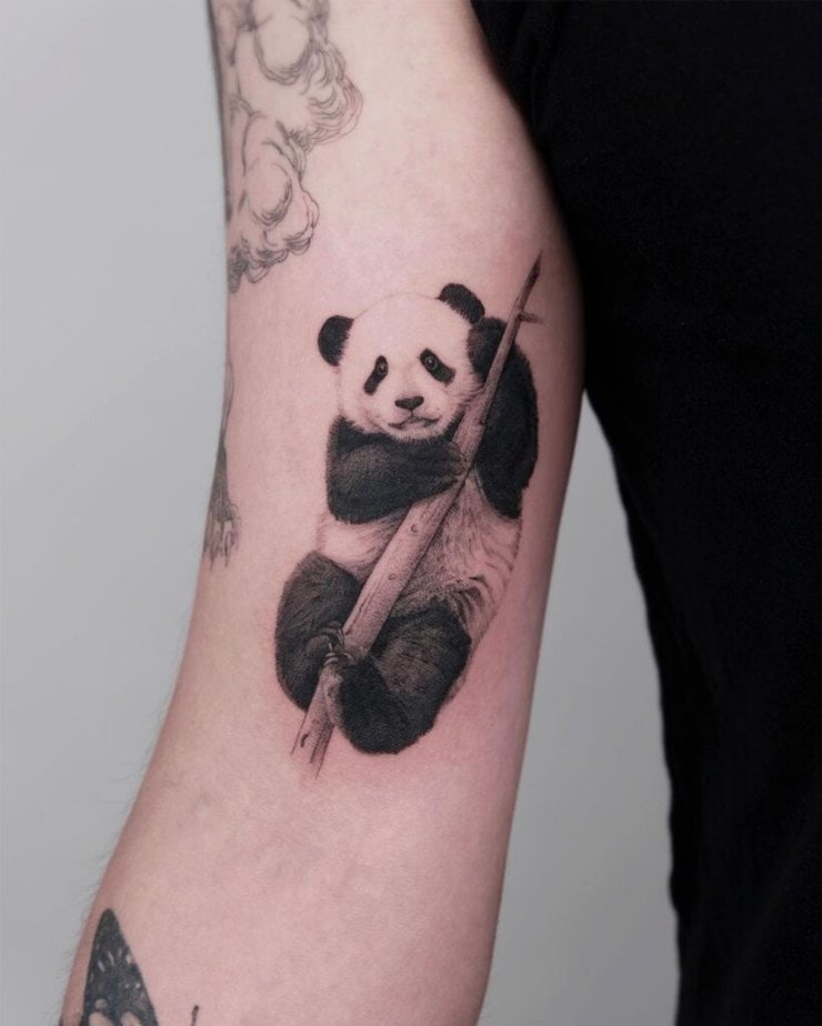 18. Eine Tätowierung eines Pandas, der sich an einem Bambuszweig festhält