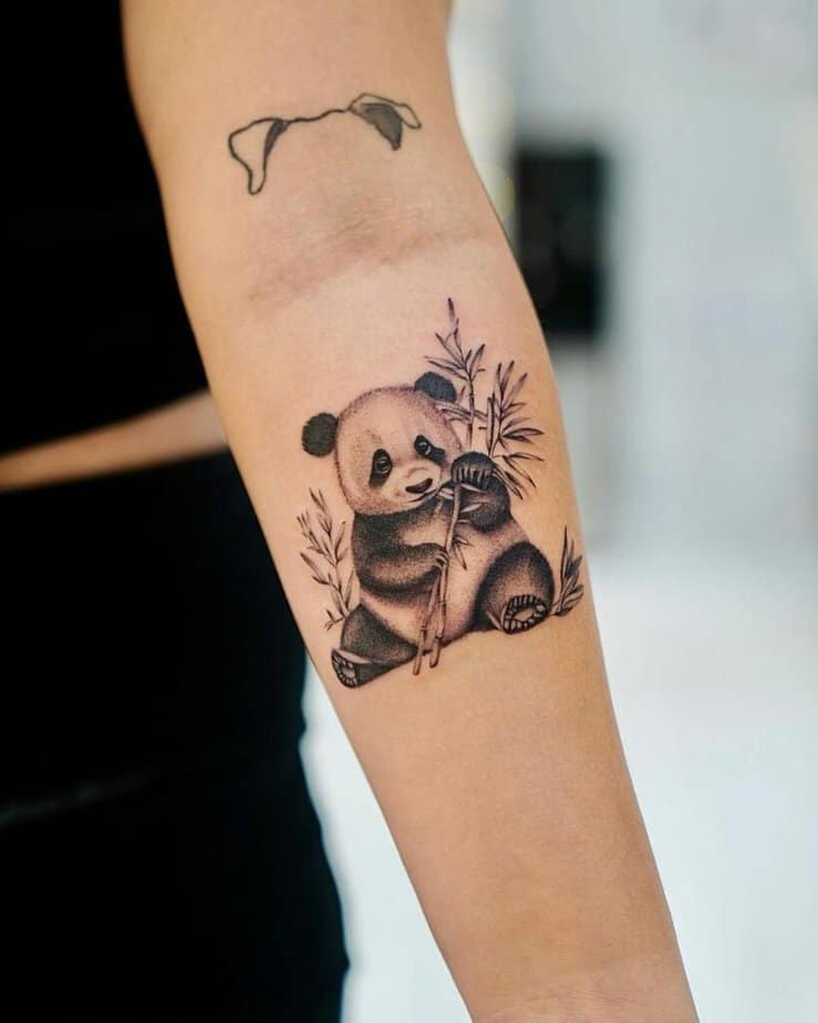 19. Eine Tätowierung eines Pandas, umgeben von Bambuszweigen 