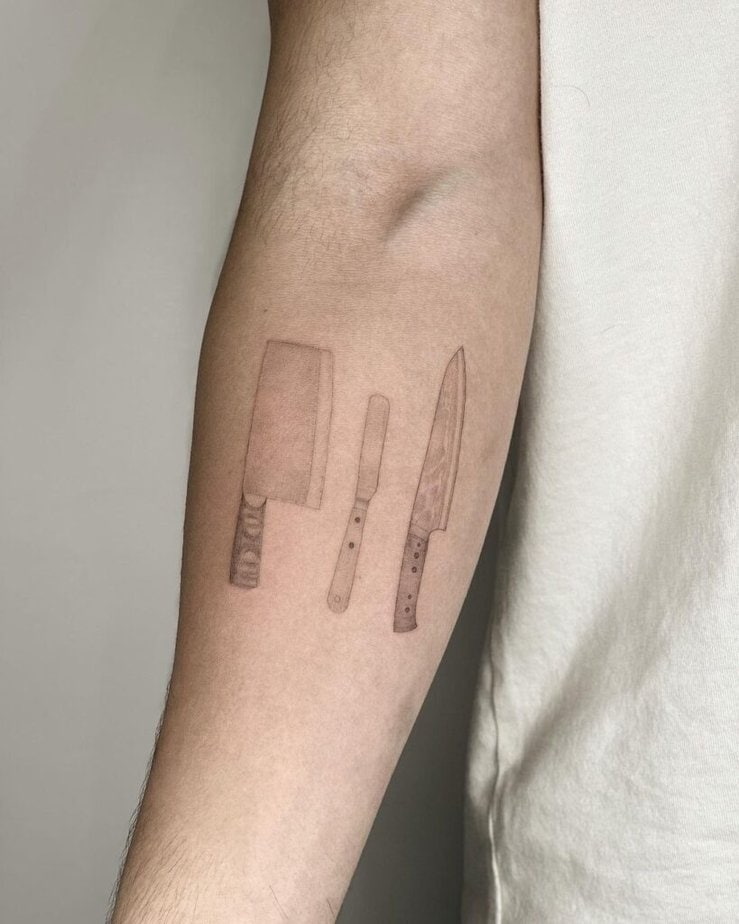 9. Eine Tätowierung mit Küchenmessern auf dem Unterarm