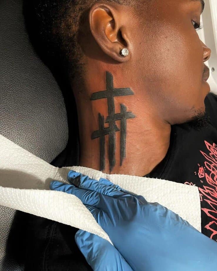 Ein minimalistisches Kreuz-Tattoo am Hals 