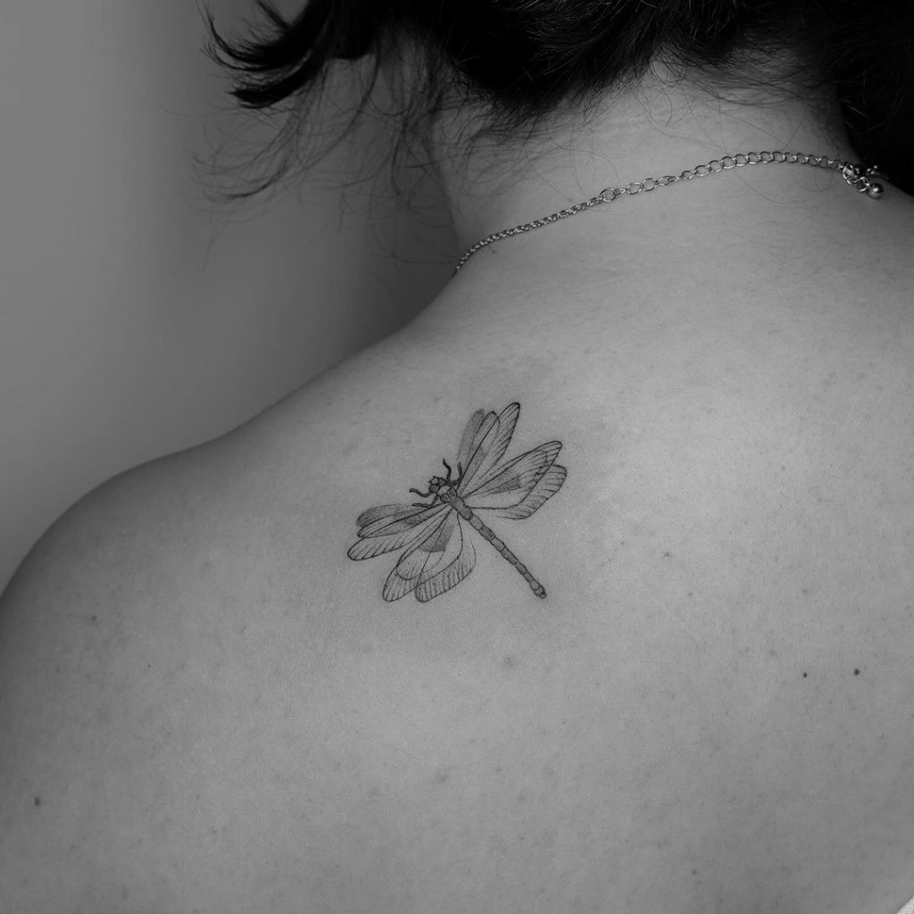Ein flatterndes Libellen-Tattoo auf der Rückseite der Schulter