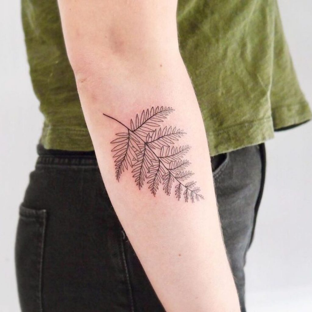 Ein Farn-Tattoo auf dem Unterarm in Linienform