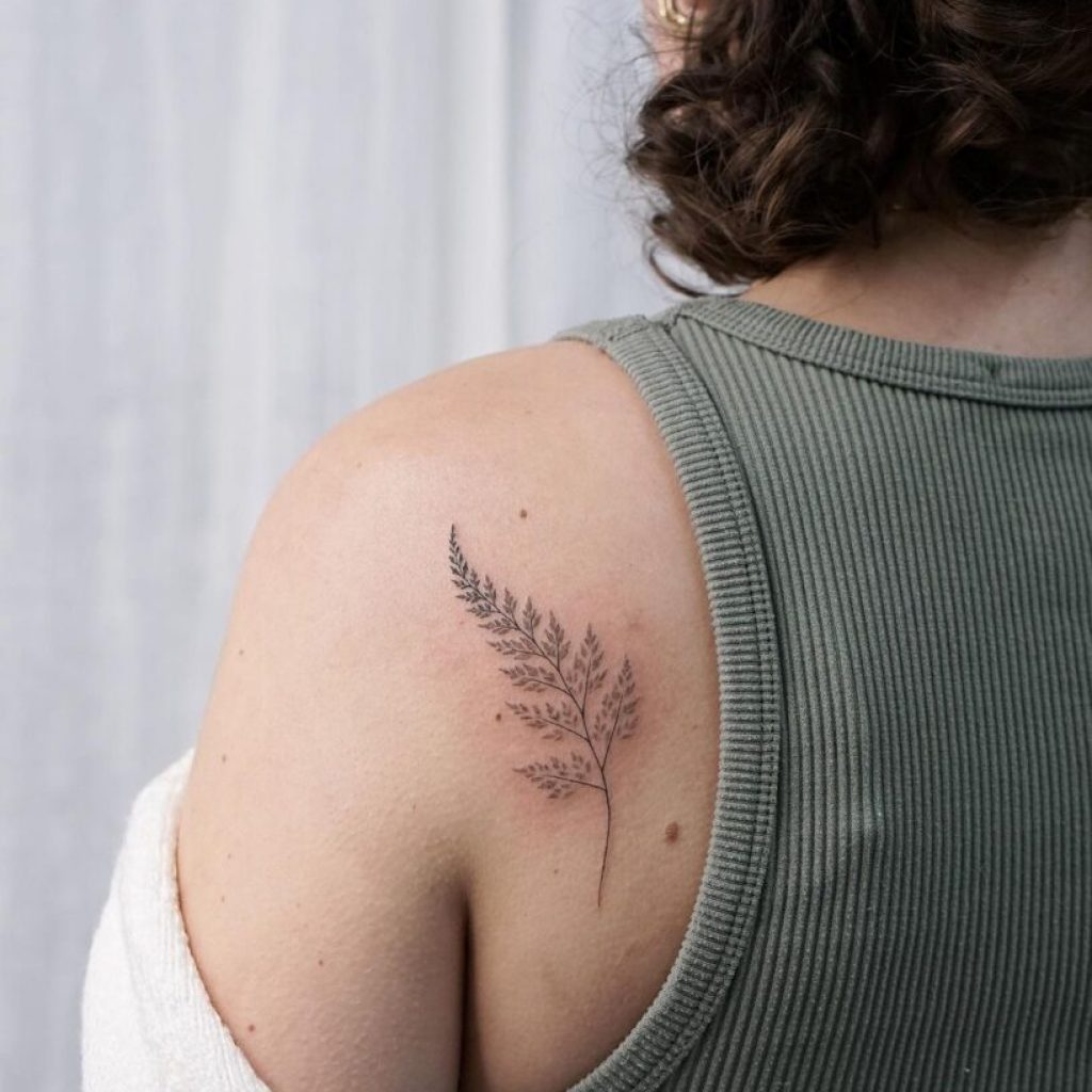 Ein Farn-Tattoo auf der Rückseite der Schulter