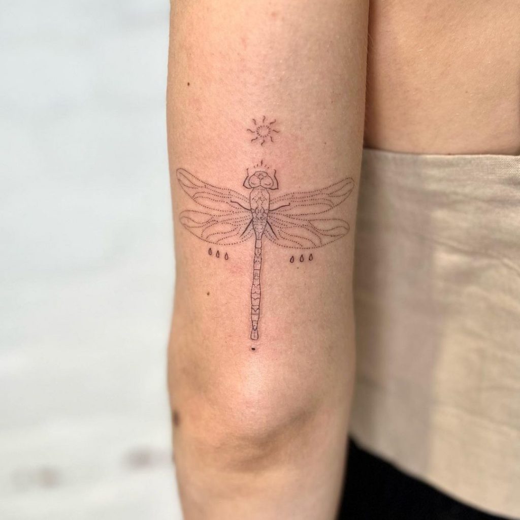 Ein sanftes und subtiles Libellen-Tattoo auf der Rückseite des Arms