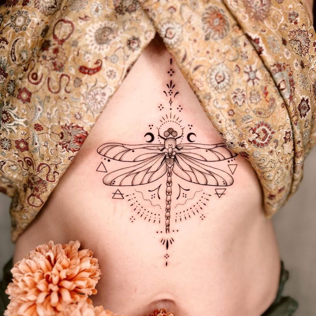 Eine ornamentale Tätowierung einer Libelle auf dem Brustbein