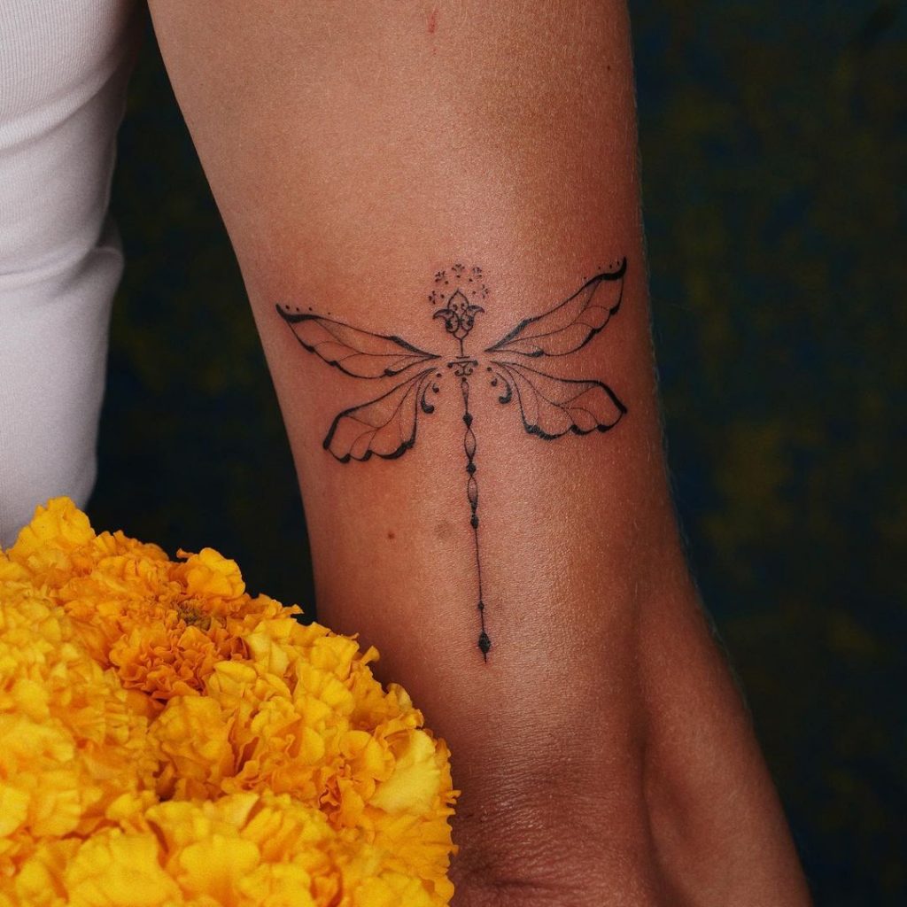 Eine ornamentale Tätowierung einer Libelle auf der Rückseite des Arms