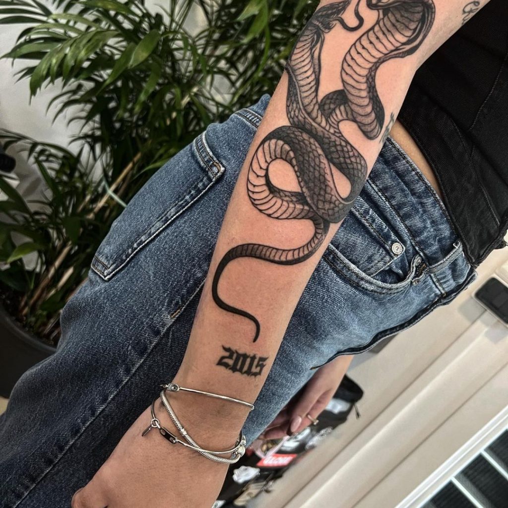 Eine zweiköpfige Kobra-Tätowierung auf dem Unterarm