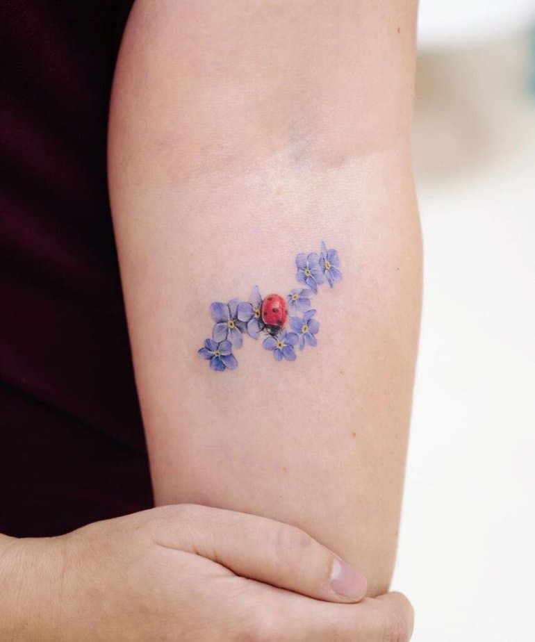 8. Ein Marienkäfer-Tattoo mit einer Vergissmeinnicht-Blume