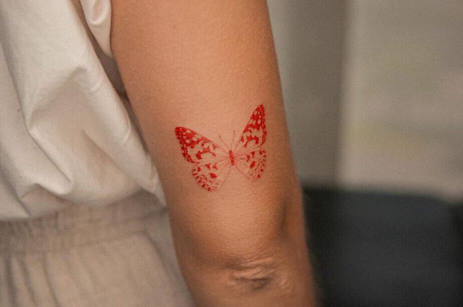 1. Ein zarter roter Schmetterling als Tattoo 