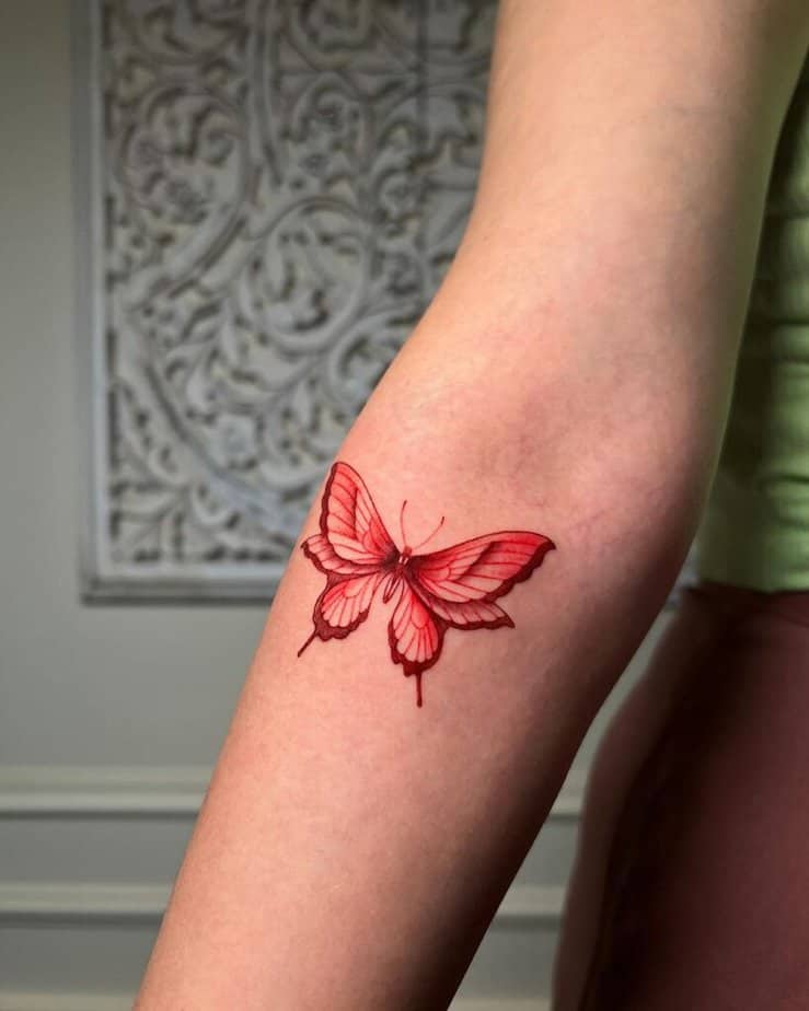 14. Ein detailliertes rotes Schmetterlingstattoo auf dem Unterarm