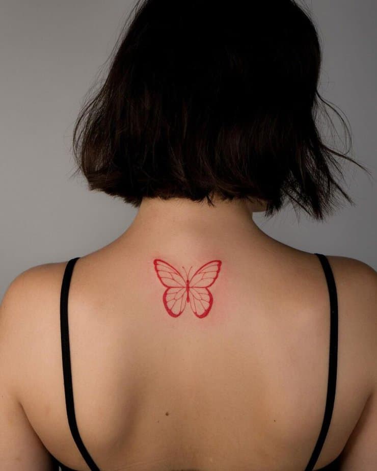 25. Eine feinlinige rote Schmetterlingstätowierung auf dem Rücken