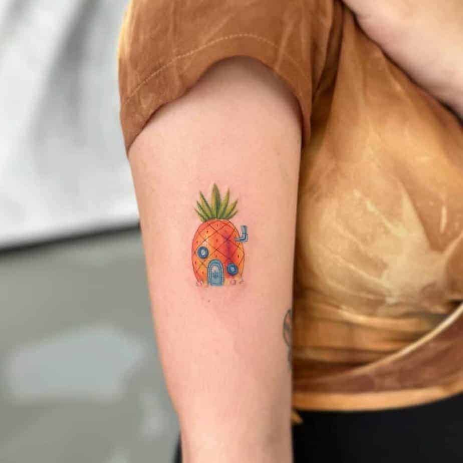 20. Ein buntes Tattoo des Ananas-Hauses auf dem Oberarm