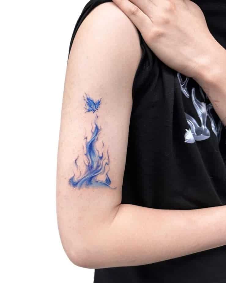 21. Ein blaues Feuer-Tattoo mit einem Schmetterling auf dem Oberarm