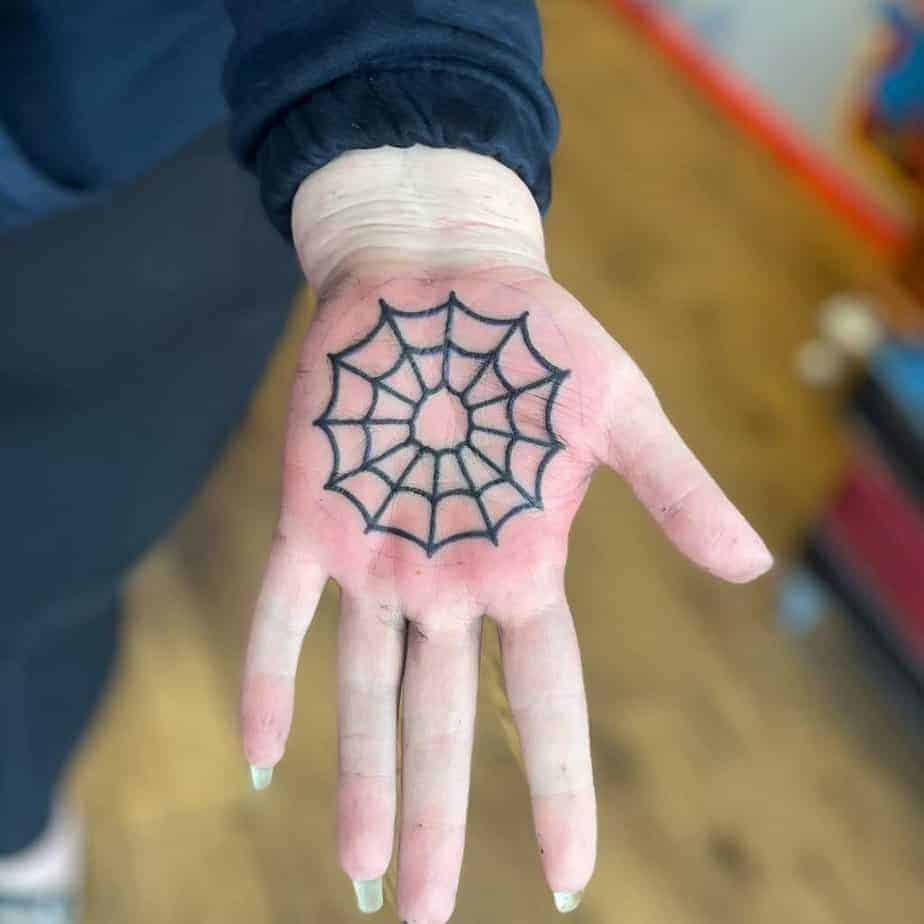 16. Ein Spinnennetz-Tattoo auf der Handfläche