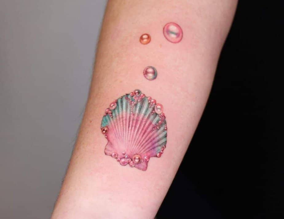 7. Ein Tattoo mit einer rosa Muschel, die mit schillernden Perlen besetzt ist