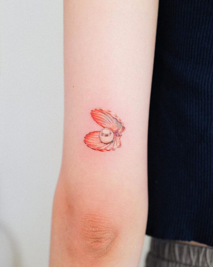 10. Ein Tattoo einer orangefarbenen Muschel mit einer Perle