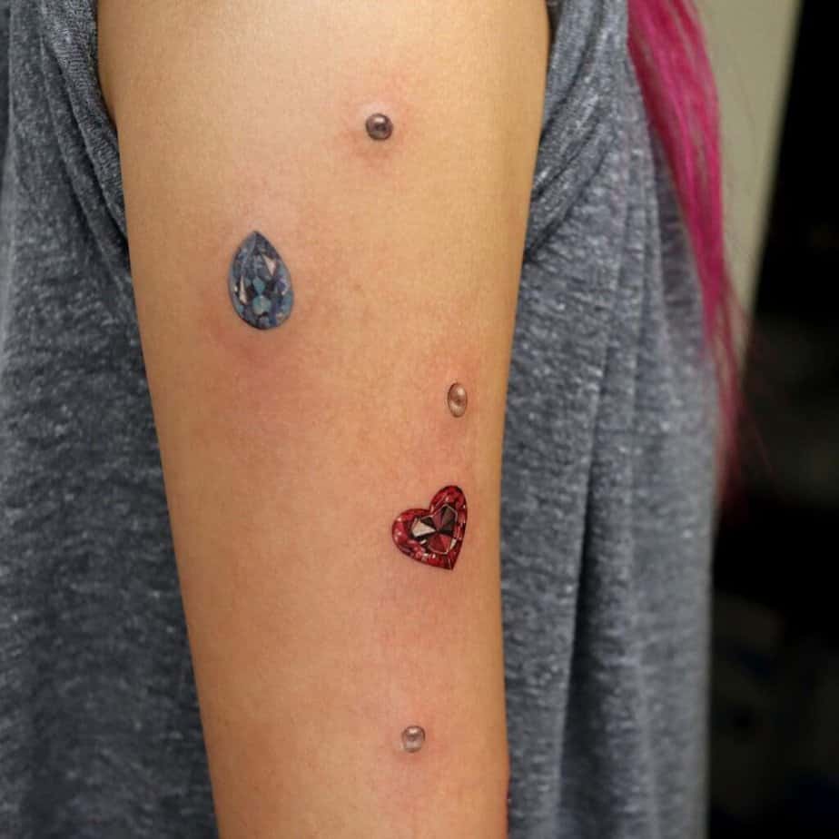 16. Ein Tattoo mit Perlen und Edelsteinen auf dem Oberarm