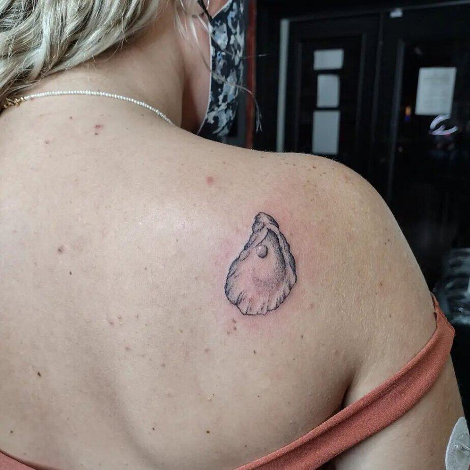 19. Ein Tattoo mit einer Austernperle auf der Rückseite der Schulter