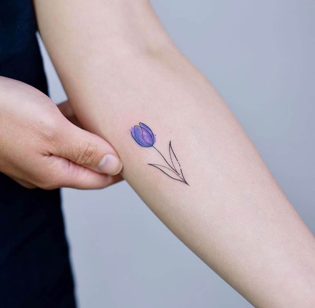 10. Ein Linientattoo mit einer lila Tulpe auf dem Unterarm
