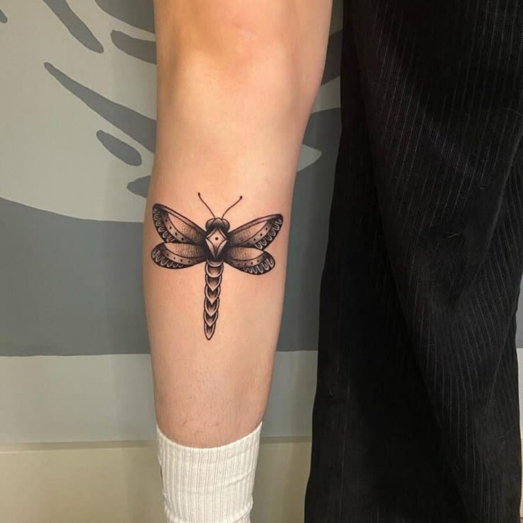 Ein Libellen-Tattoo auf dem Schienbein
