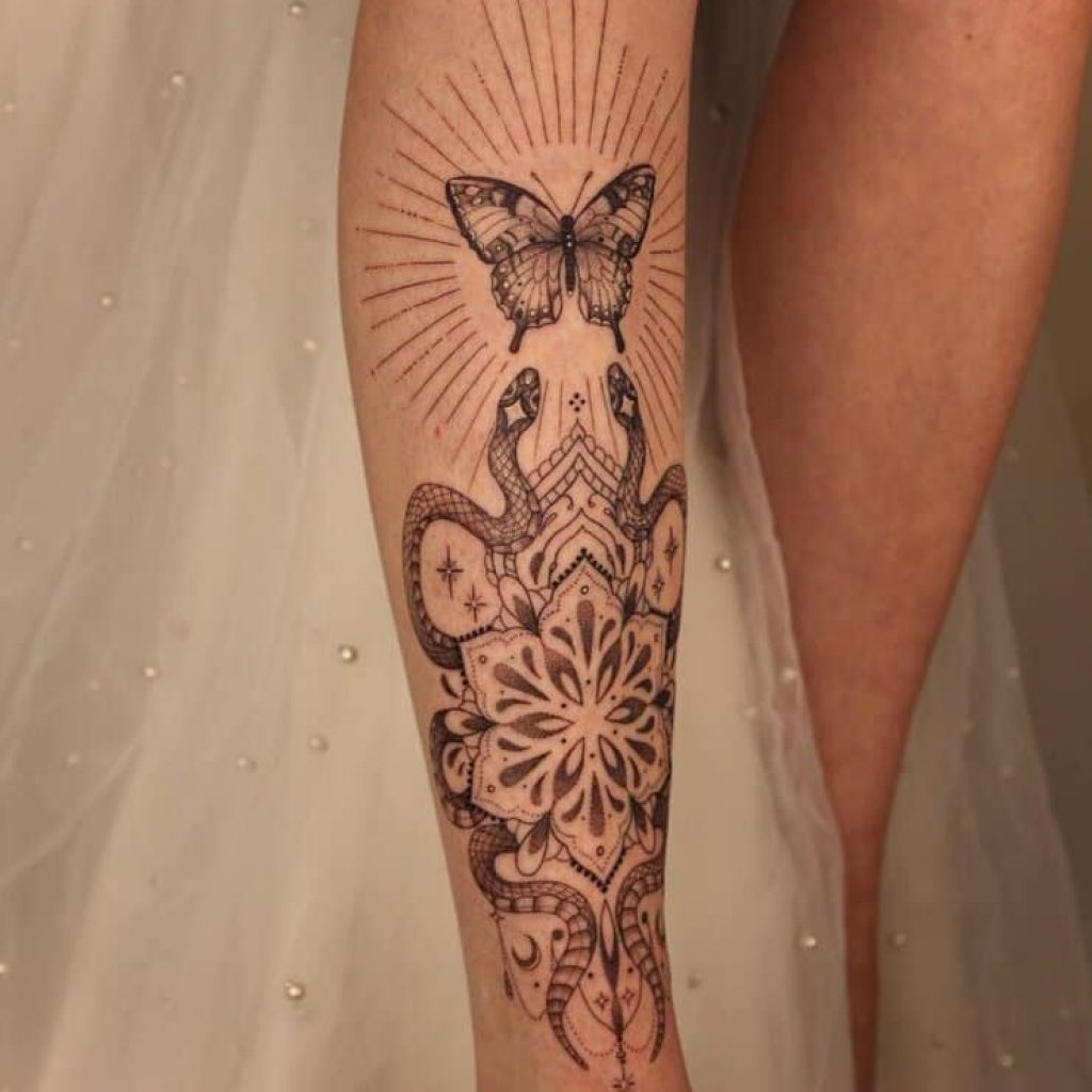 Ein ornamentales Schienbein-Tattoo mit Schlangen, Ornamenten und einem Schmetterling