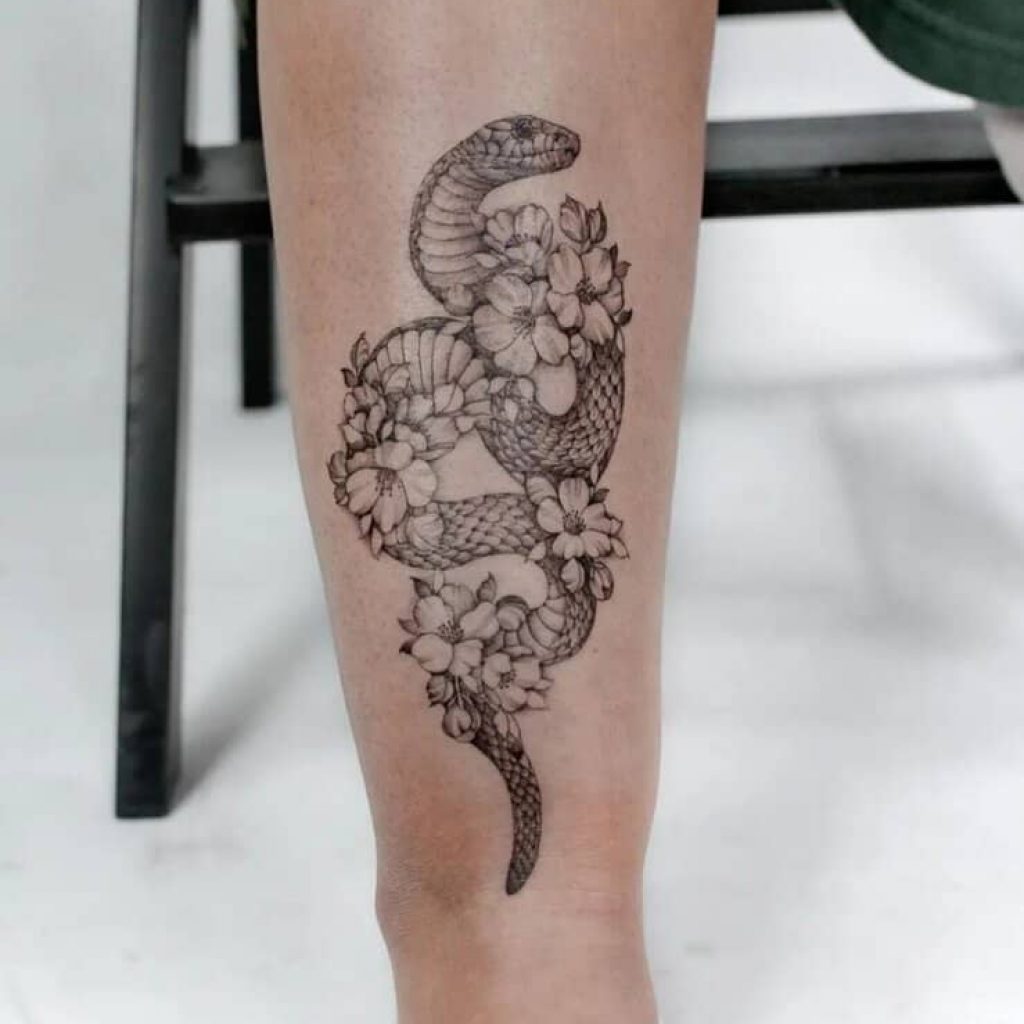 Schienbein-Tattoo einer von Blumen umgebenen Schlange