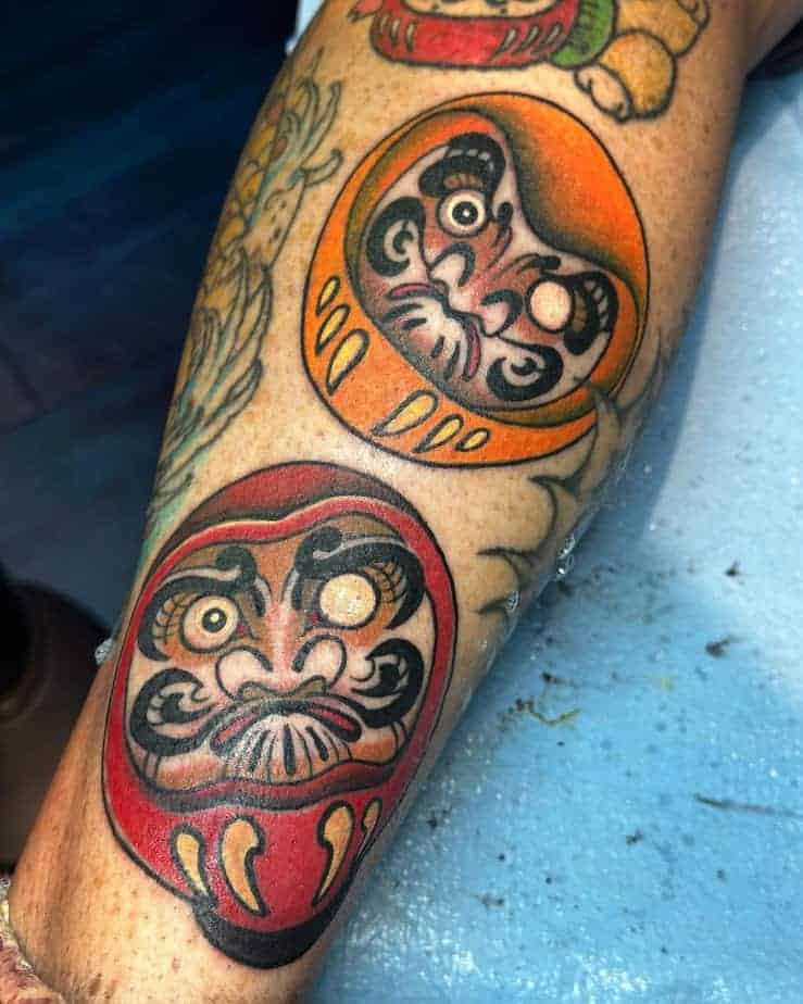 8. Rote und orangefarbene Daruma-Tattoos