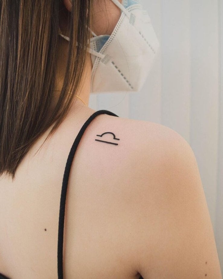 13. Ein minimalistisches Waage-Symbol-Tattoo auf dem Rücken