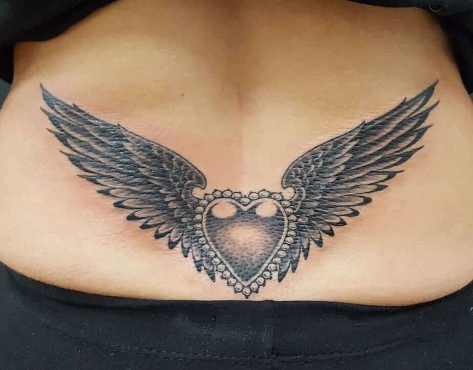 7. Elegantes Tattoo mit Herz und Flügeln auf dem unteren Rücken