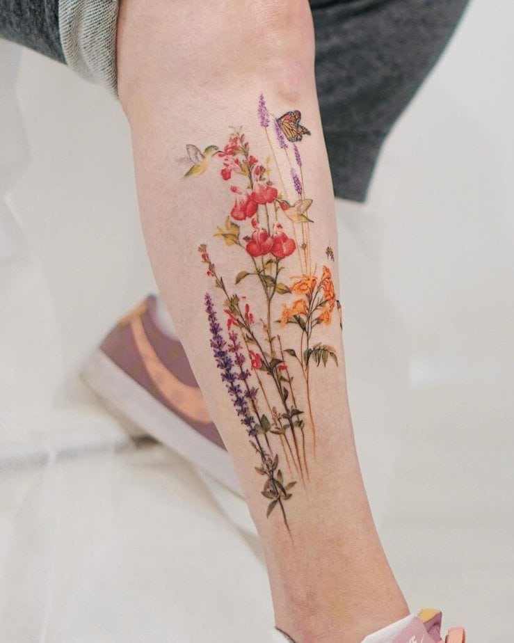 17. Ein Kolibri-Beintattoo mit Blumen