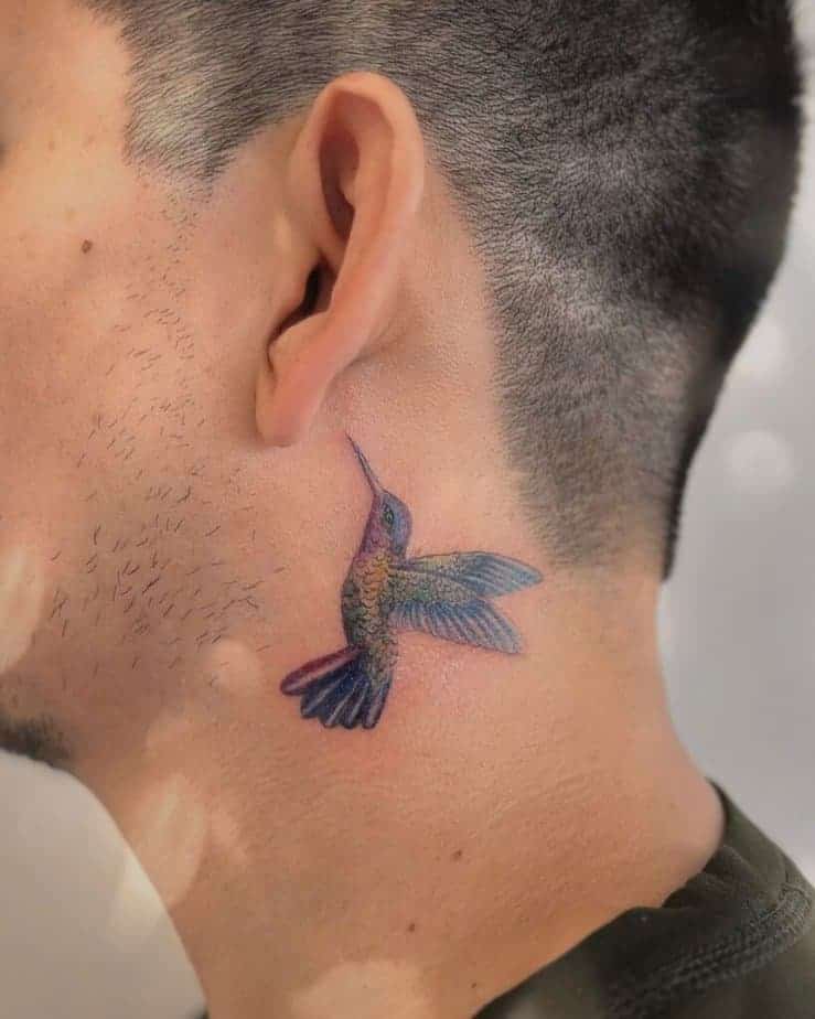 22. Ein farbenfrohes Hinter-dem-Ohr-Kolibri-Tattoo